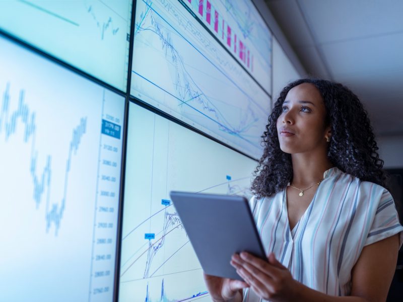 UK, York, Businesswoman with tablet looking at charts on interactive screens